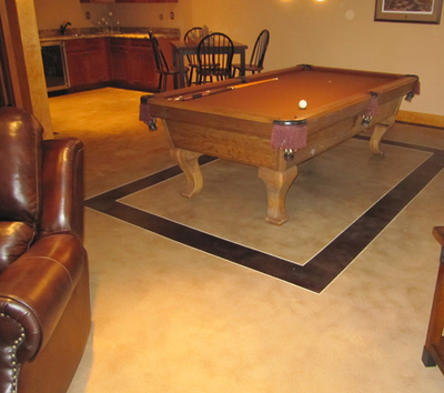 grey stained concrete in basement with billiards table sitting inside concrete stained black square.
